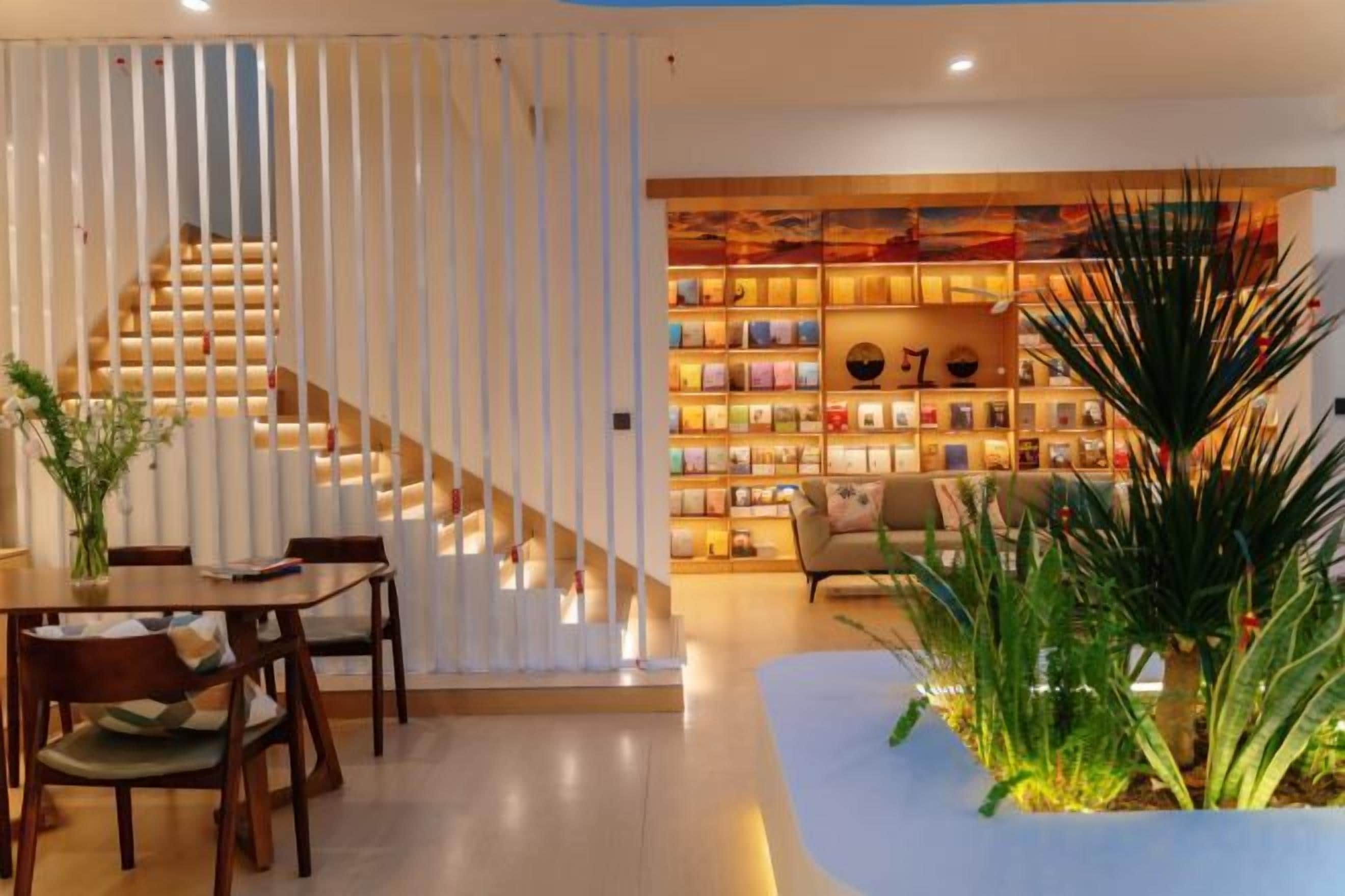 A modern interior with a staircase, a dining area, and a bookshelf.