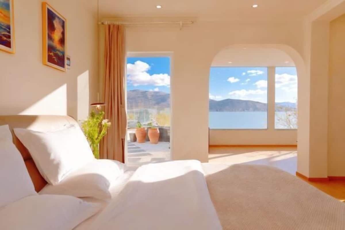 A bedroom with a bed, a view of the outdoors, and a door leading outside.