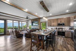 Une cuisine spacieuse dotée d’un grand îlot central, d’appareils électroménagers modernes et offrant une vue sur les montagnes.