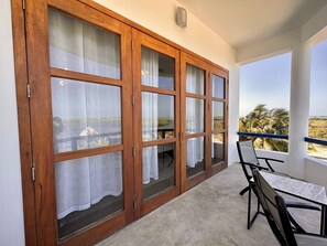Ein Balkon mit Blick auf Palmen und einen Strand.