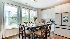 A modern kitchen with white cabinets, a large island, and a dining area with a table set for four.