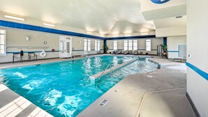 An indoor swimming pool with clear water, a lifeguard chair, and a blue safety line.