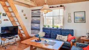 A cozy living room with a wooden staircase, a sofa, a coffee table, and a TV on a stand. - Gorgeous home in Ljung with kitchen (Ljung)