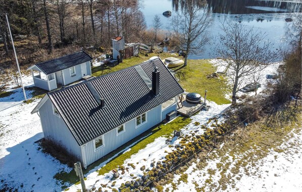 A two-story house with a metal roof, a small shed, and a pond in the background. - Gorgeous home in Ljung with kitchen (Ljung)