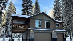 Une maison à deux étages avec un balcon, un garage et une façade en pierre.