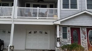 A two-story building with a garage, a balcony, and a stone facade.