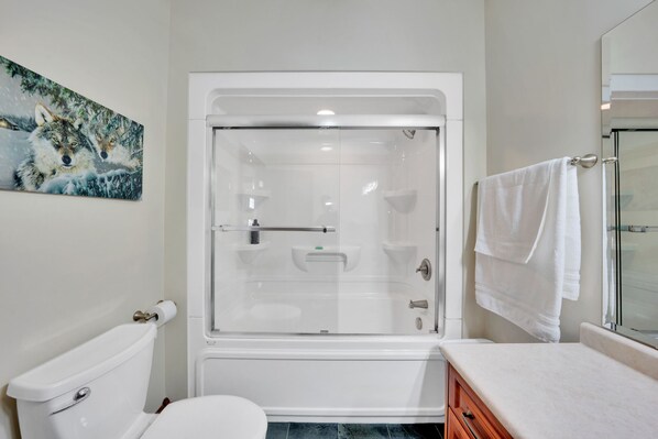 Ein Badezimmer mit Duschkabine, Toilette, Waschbecken und Handtuchhalter.