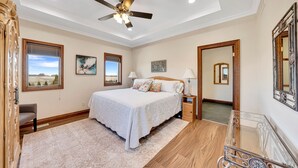 A bedroom with a bed, bedside tables, a ceiling fan, a window, and a mirror.