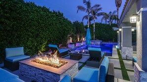 Une terrasse extérieure avec un foyer, des sièges et une piscine.