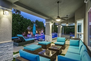 An outdoor patio with seating, a pool, and a ceiling fan.