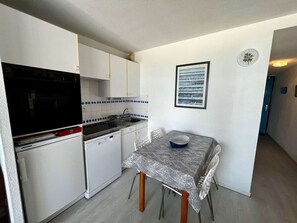 A compact kitchen with white cabinets, a black stove, and a tiled backsplash.