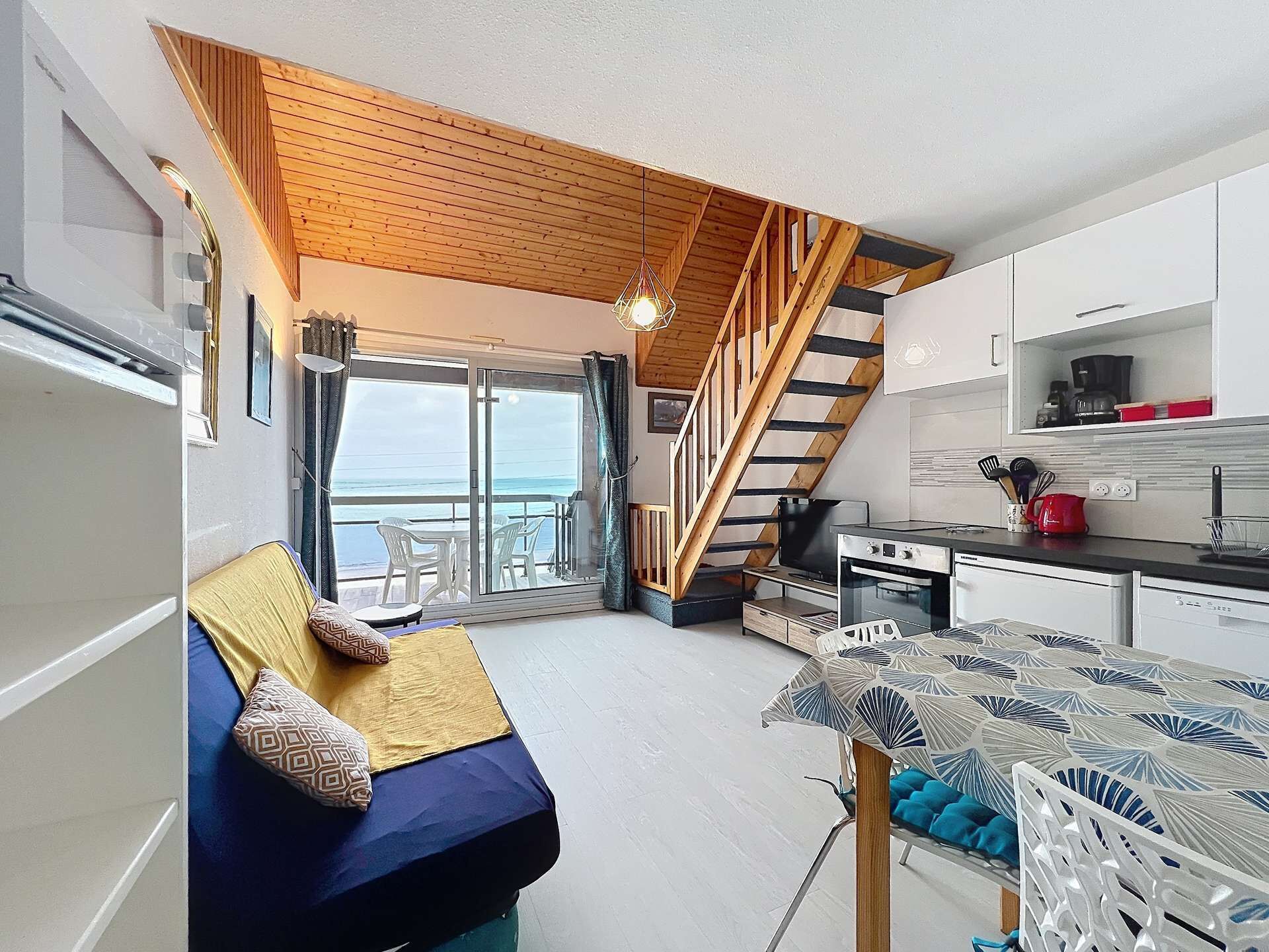Een ruimtelijk ingerichte leefruimte met kitchenette, een eethoek en een slaapkamer met uitzicht.