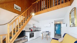 Ein modernes Interieur mit einer Holztreppe, einer Küche, einem Essbereich und einem Wohnzimmer mit einer Couch.