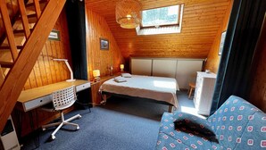 Ein kleines Zimmer mit Bett, Schreibtisch und Stuhl.