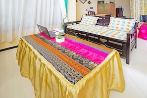 A bedroom with a bed, a laptop on a table, and a patterned table runner. - Spot On 91551 Gwen Syariah Homestay (Tanjung Pinang)
