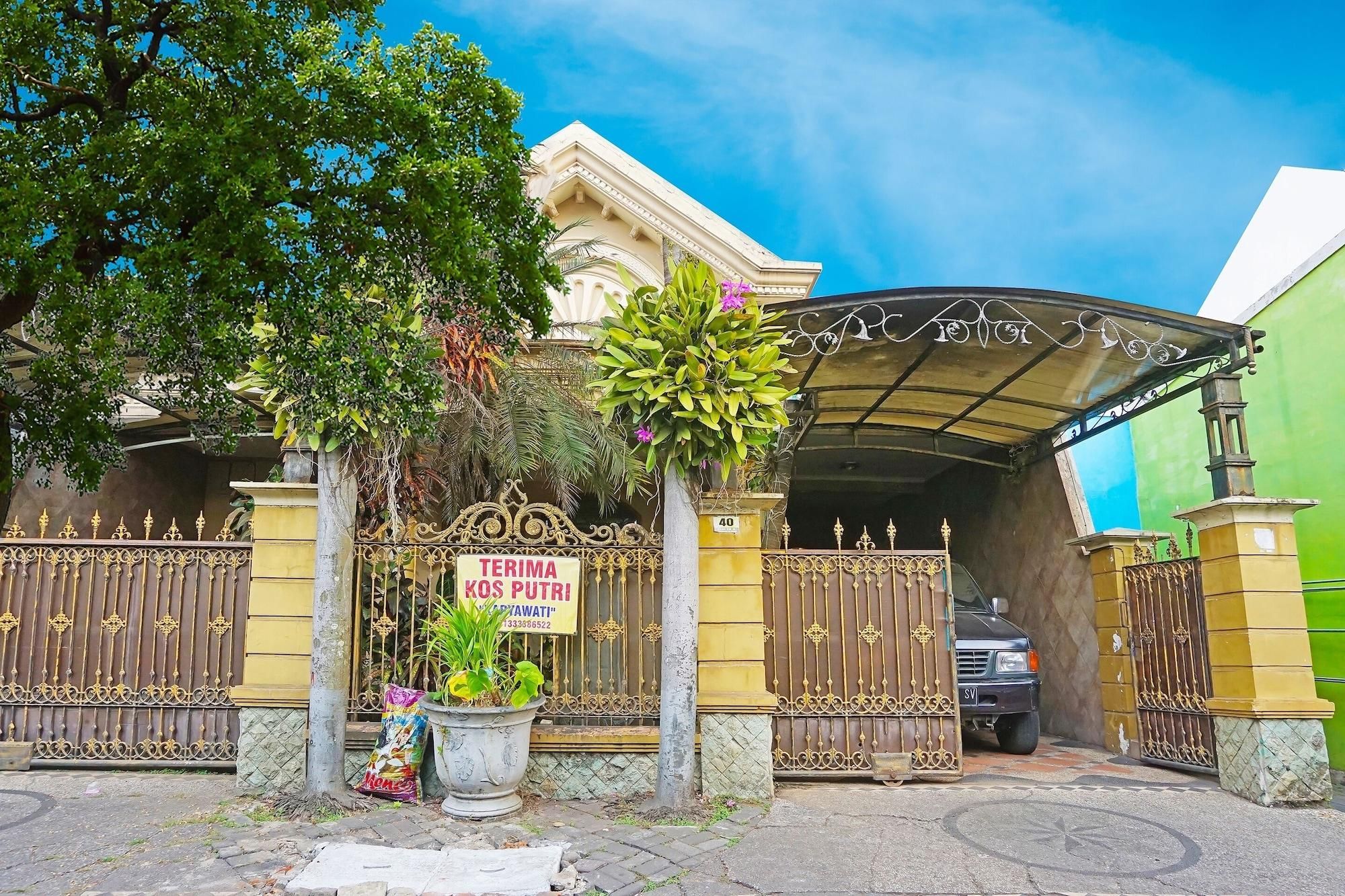 A gated entrance with a sign reading 'TERIMA KOS PUTRI' and a vehicle parked inside.