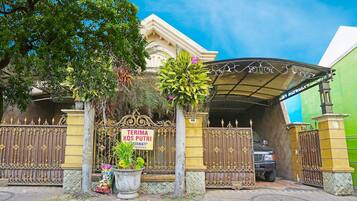 A gated entrance with a sign reading 'TERIMA KOS PUTRI' and a vehicle parked inside.