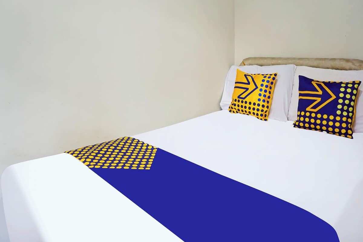 Una cama con ropa blanca y dos almohadas decorativas con diseños geométricos.