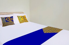 A bed with white bedding, two pillows with geometric patterns, and a blue bed runner. - Spot On 91551 Gwen Syariah Homestay (Tanjung Pinang)