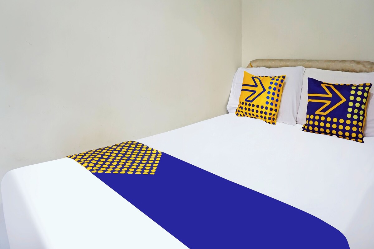 A bed with white bedding and two decorative pillows with geometric patterns.