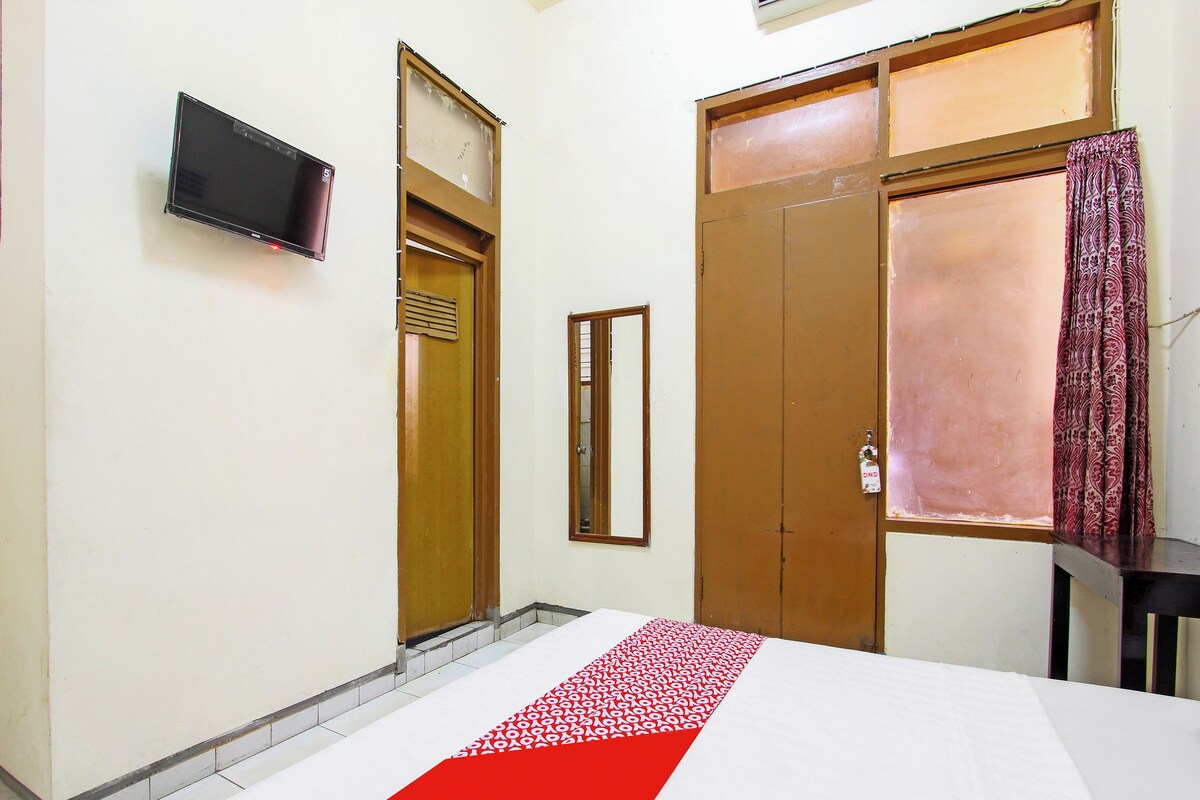 Ein Hotelzimmer mit Bett, Fernseher, Kleiderschrank und einem fenster mit Vorhängen.