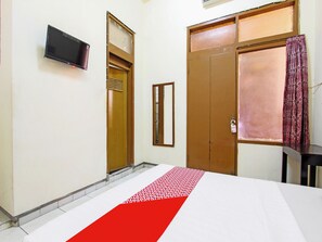Ein Hotelzimmer mit Bett, Fernseher, Kleiderschrank und einem fenster mit Vorhängen.