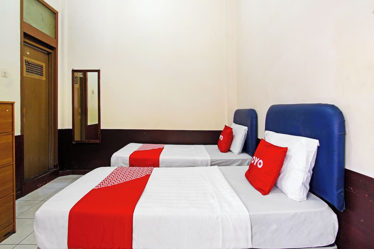 A hotel room with two beds, each with a red and white bedspread, and a mirror on the wall.