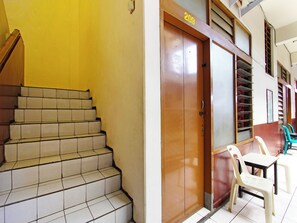 Un escalier menant à une porte portant le numéro 209, une petite table avec des chaises et une fenêtre avec des stores.