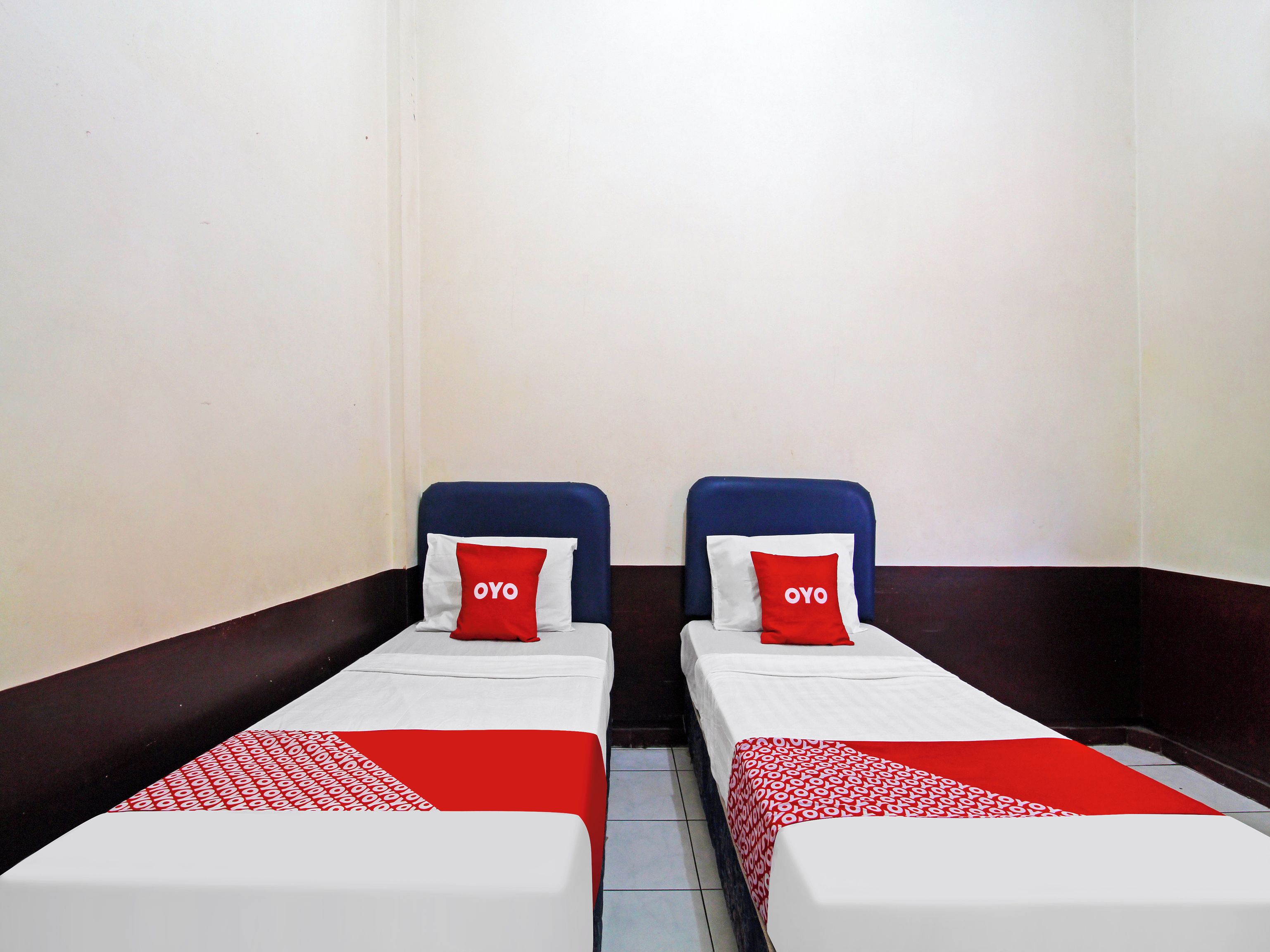 Two single beds with red and white bedding, a dark brown wall, and a white ceiling.