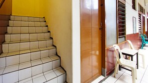 A staircase leading to a wooden door with the number 209, a small table with chairs, and a window with blinds.