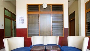A waiting area with a sofa set, two small tables, and a wall clock.