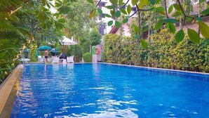 A swimming pool surrounded by lush greenery, with lounge chairs and umbrellas. - The Lokal Hotel Phuket (Patong)