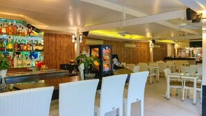 A bar area with a variety of liquor bottles, a decorative fish tank, and white wicker chairs. - The Lokal Hotel Phuket (Patong)