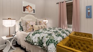 A bedroom with a bed, a nightstand, a lamp, a chair, and a window with curtains. - Bay St. Louis Cottage located less than a mile from Downtown!!! (Bay St. Louis)
