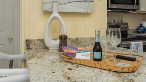 A kitchen counter with a tray holding a bottle, glasses, and a card. - Bay St. Louis Cottage located less than a mile from Downtown!!! (Bay St. Louis)