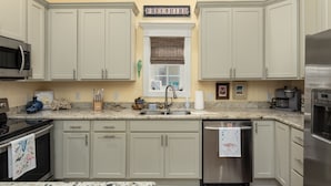 A kitchen with light-colored cabinets, a stainless steel refrigerator, and a microwave. - Bay St. Louis Cottage located less than a mile from Downtown!!! (Bay St. Louis)