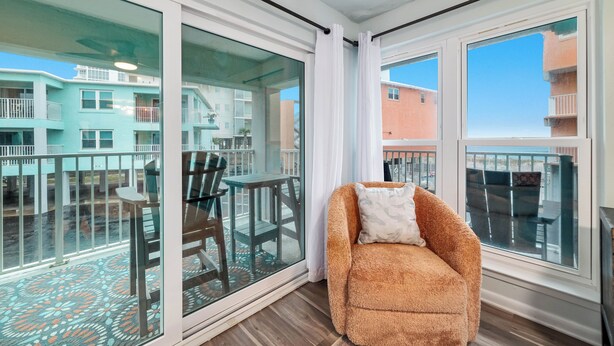 Un balcon avec une porte vitrée, une chaise marron et une table avec des chaises.