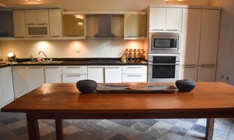 A modern kitchen with white cabinets, stainless steel appliances, and a wooden dining table.