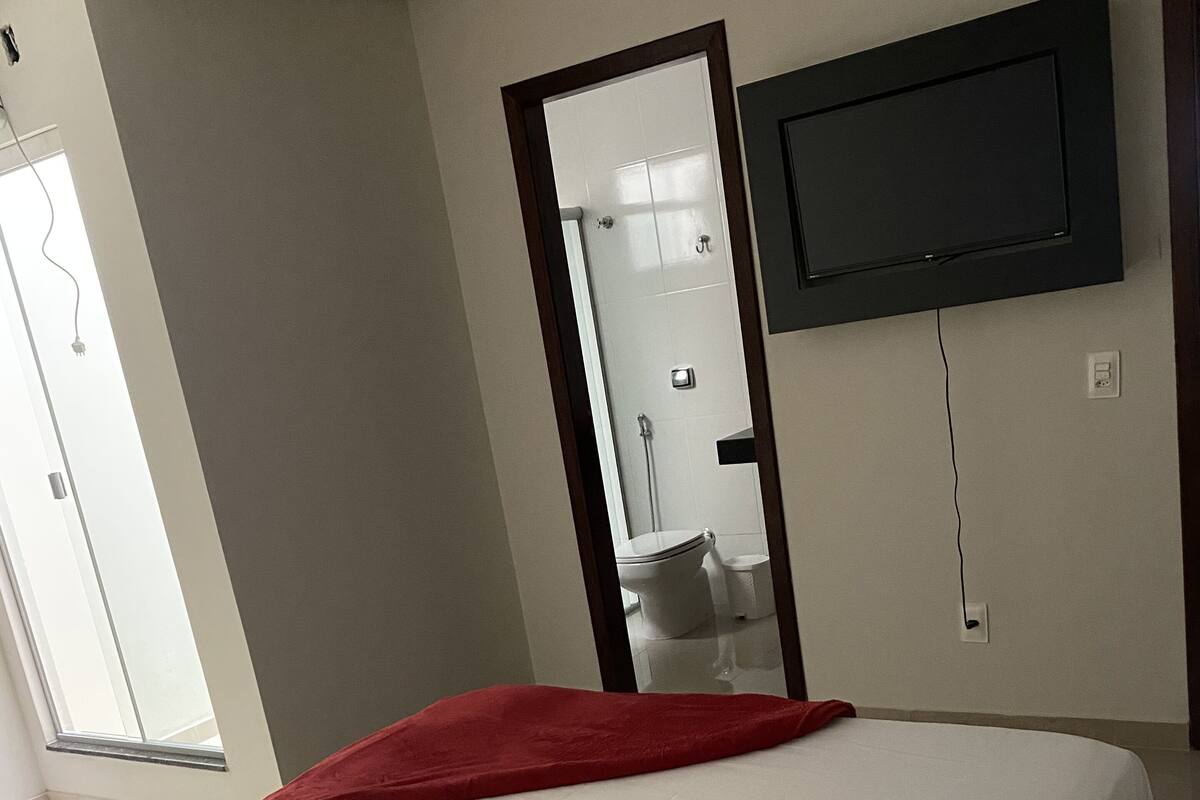 Ein Hotelzimmer mit Bett, Wandfernseher und einem Fenster für natürliches Licht.