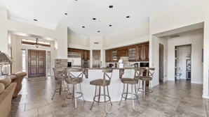 A spacious kitchen with a central island, bar stools, and modern appliances. - The Genoa House ~ Oasis in the Hills (Fountain Hills)