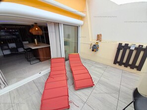 A room with a sliding glass door, a dining area with a table and chairs, and a red mat on the floor.