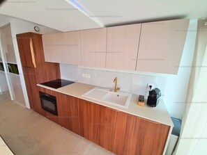 A modern kitchen with a built-in oven, a sink, and a coffee machine.