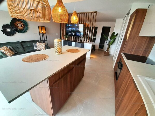 A modern kitchen with a central island, wooden cabinetry, and pendant lighting.