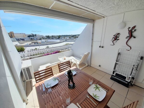 A balcony with a table set for two, a chair, and a decorative wall with two lizards. - Apartment Poème (LE CAP D AGDE)
