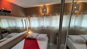 Une chambre d’hôtel avec deux lits, un grand miroir et une fenêtre avec des rideaux.