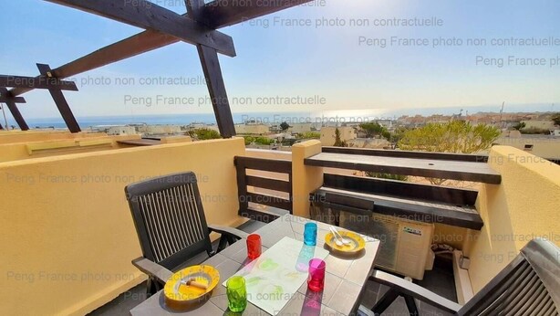Une terrasse avec une table, des chaises et un barbecue.