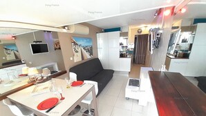 Un espace de vie compact comprenant un coin repas, une kitchenette et un canapé.