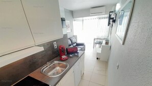 Une cuisine moderne dotée d’un évier en acier inoxydable, d’un grille-pain rouge et d’une plaque de cuisson à induction noire.