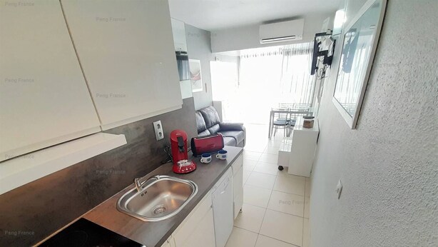 Una cocina moderna con un lavamanos de acero inoxidable, un tostador rojo y una placa de cocción por inducción negra.