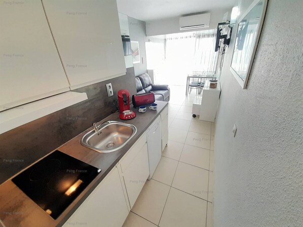 A modern kitchen with a stainless steel sink, a red toaster, and a black induction cooktop.